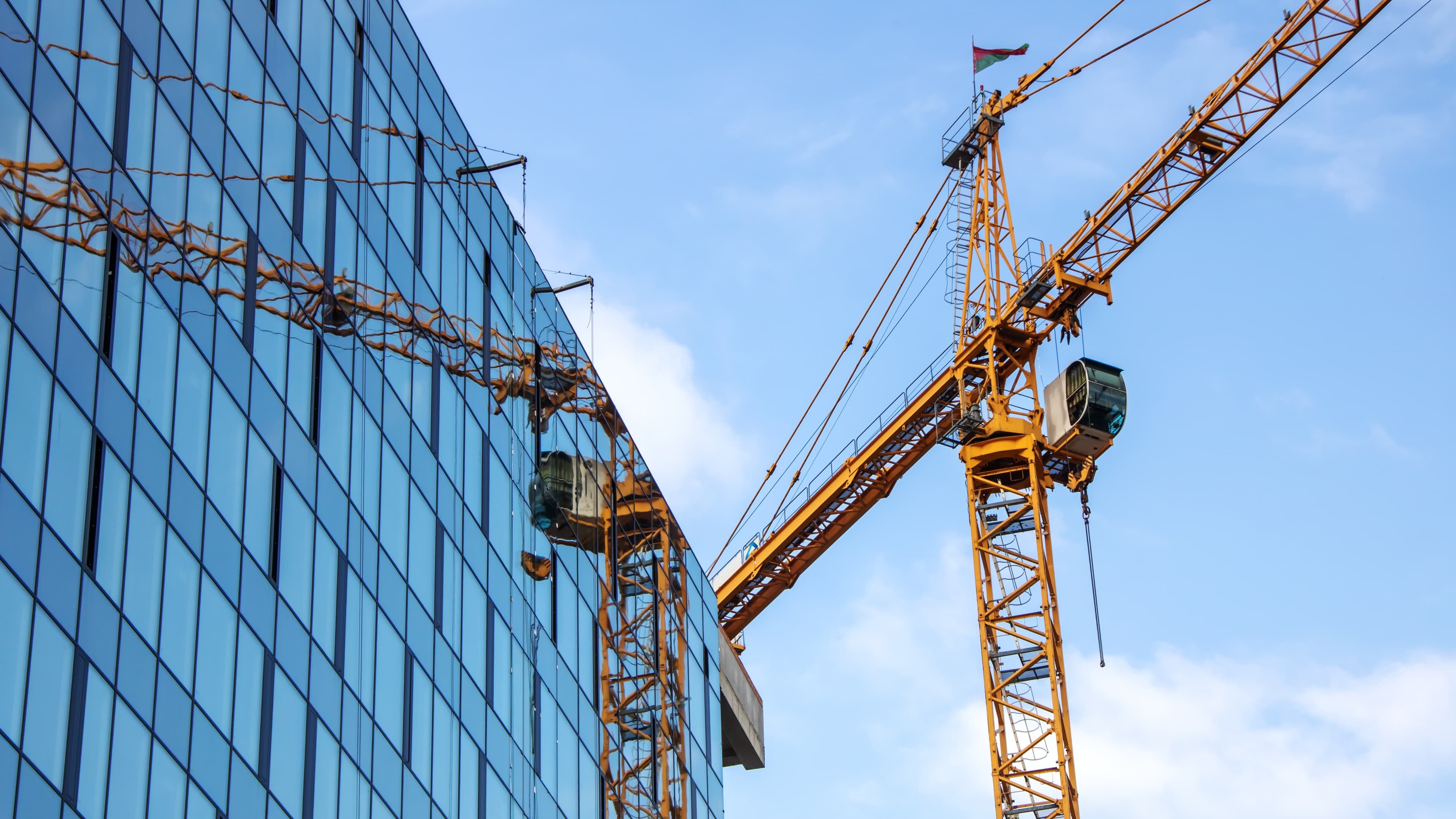 Urban construction with modern glass building and tower crane